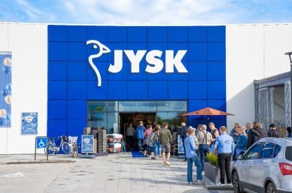 personnes rassemblées devant un magasin JYSK avec le logo blanc sur fond bleu en devanture