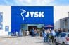 personnes rassemblées devant un magasin JYSK avec le logo blanc sur fond bleu en devanture